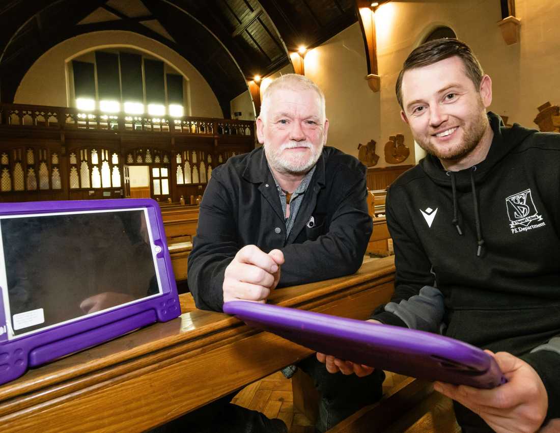 Two men looking to camera with iPads with purple frames.
