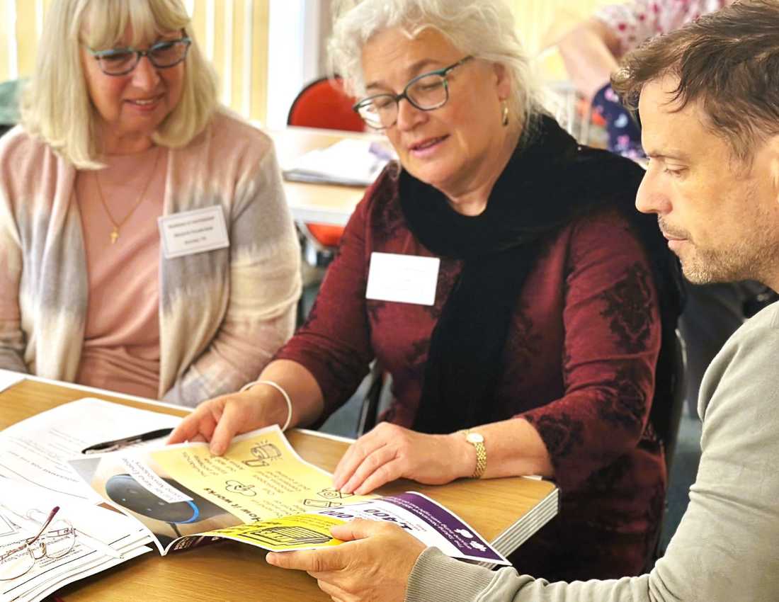 Two women look at a BWBF leaflet with a member of staff
