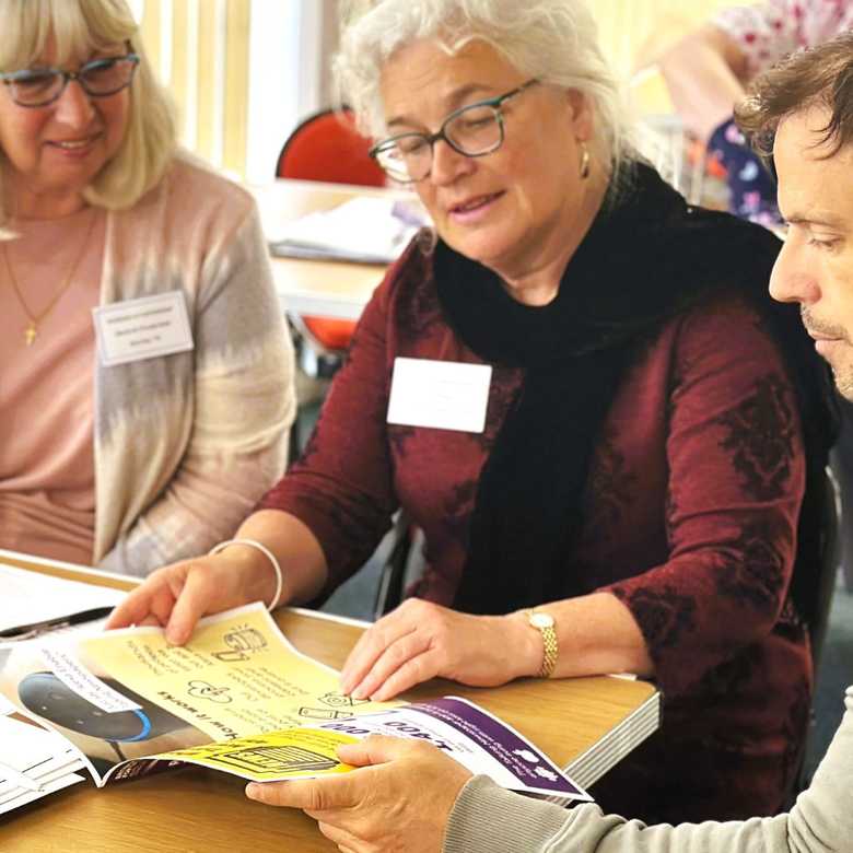 Two women look at a BWBF leaflet with a member of staff