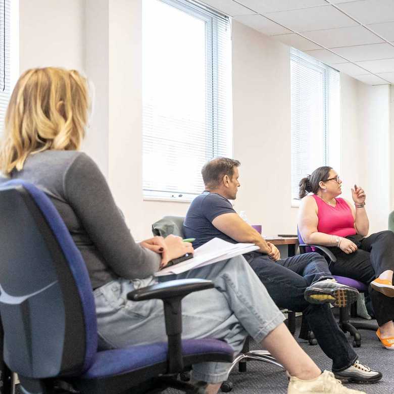 BWBF team members sit together in an office space discussing ideas at a team meeting