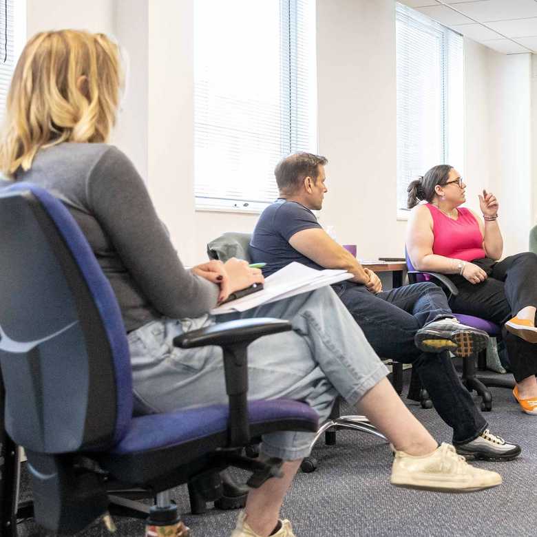BWBF team members sit together in an office space discussing ideas at a team meeting