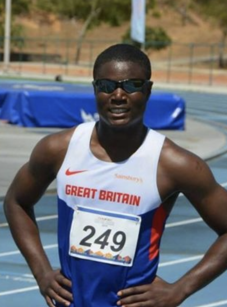 BWBF Patron Souleyman Bah is standing on an athletics track. He is wearing an athlete's vest and sunglasses.
