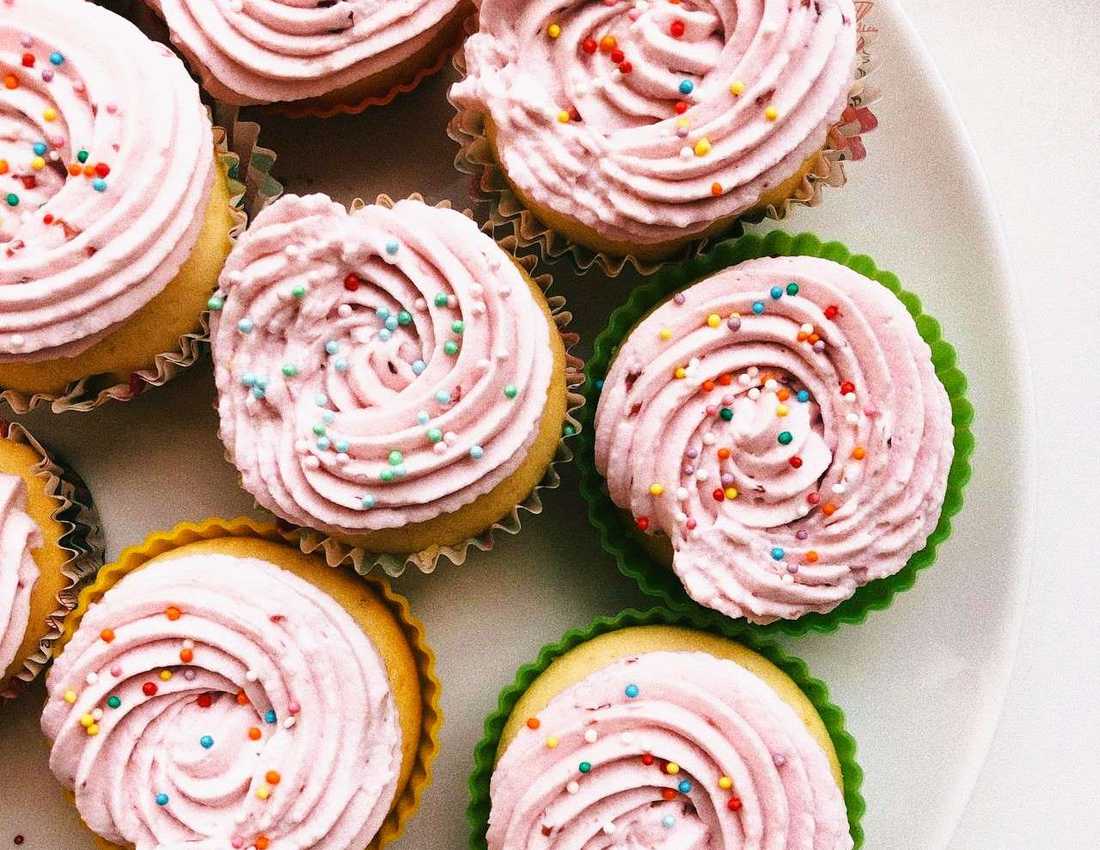 Plate of cupcakes with pink icing and coloured sprinkles