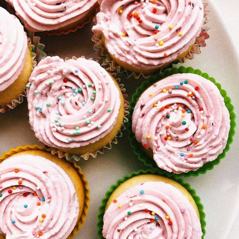 Plate of cupcakes with pink icing and coloured sprinkles